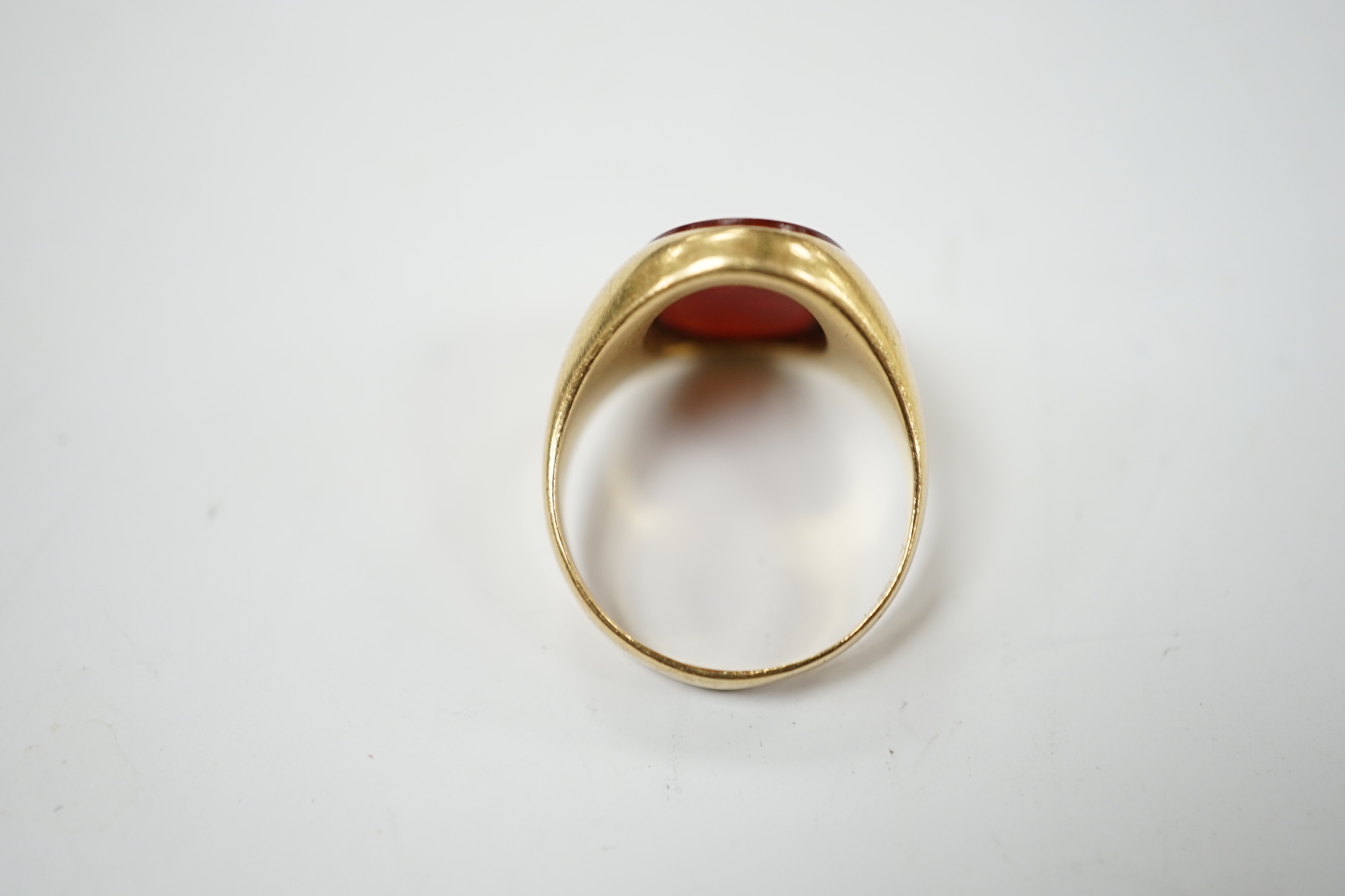 An 18ct and oval intaglio carnelian set signet ring, carved with family crest and motto, size K, gross weight 6.9 grams.